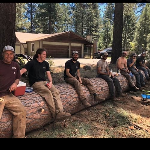 Kosich crew members taking a lunch break on a felled log at a job site