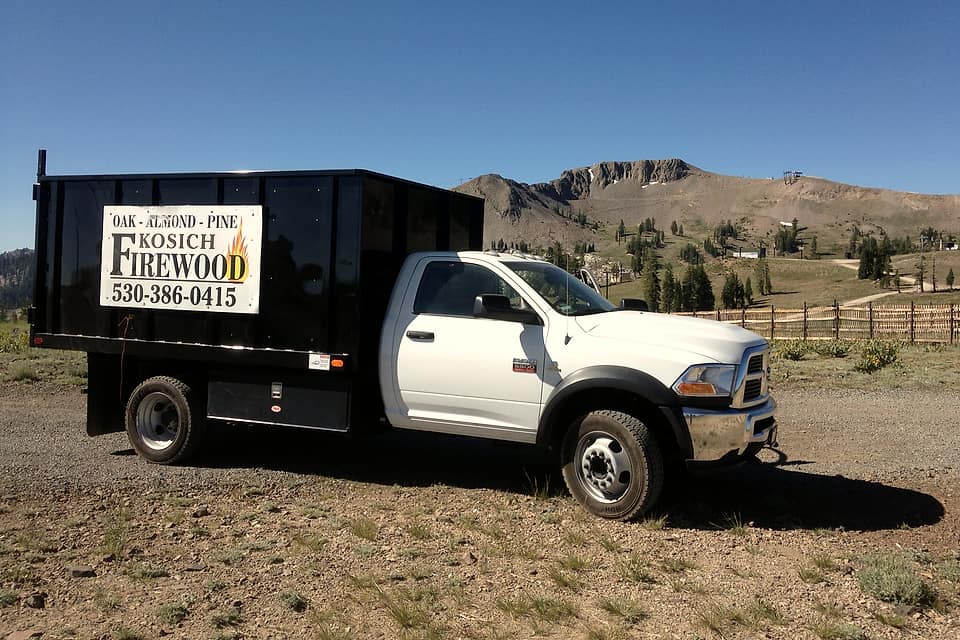 Kosich Firewood delivery truck with its Oak, Almond, Pine sign, parked below a mountain ridge